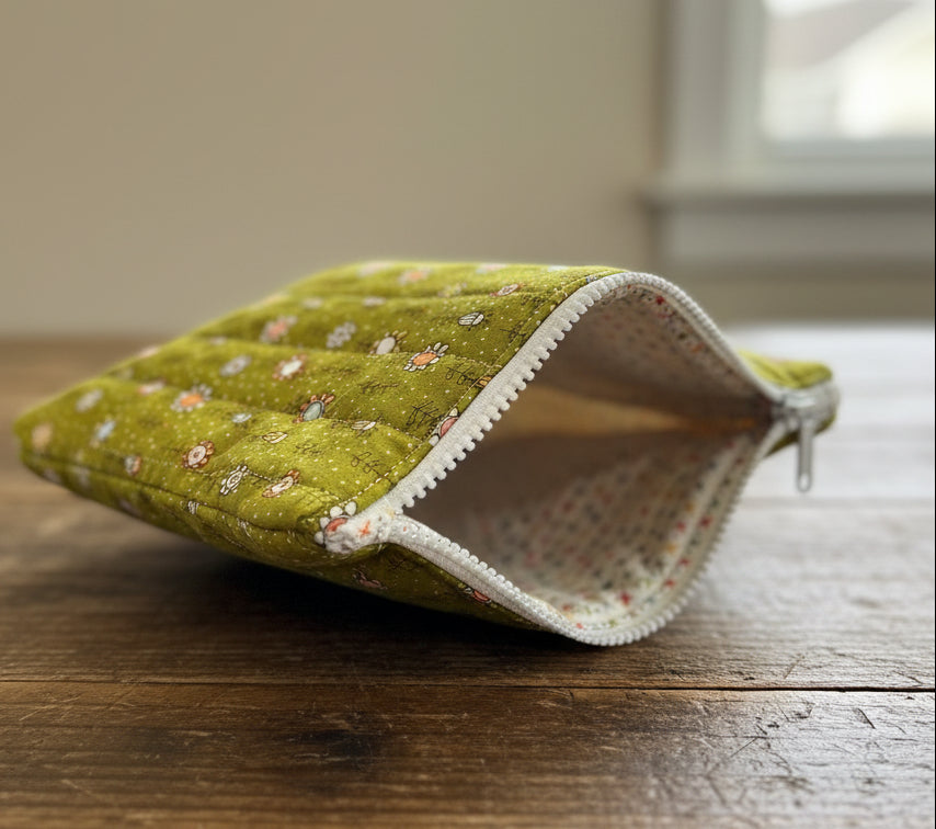 Green quilted pouch with floral pattern on a white background