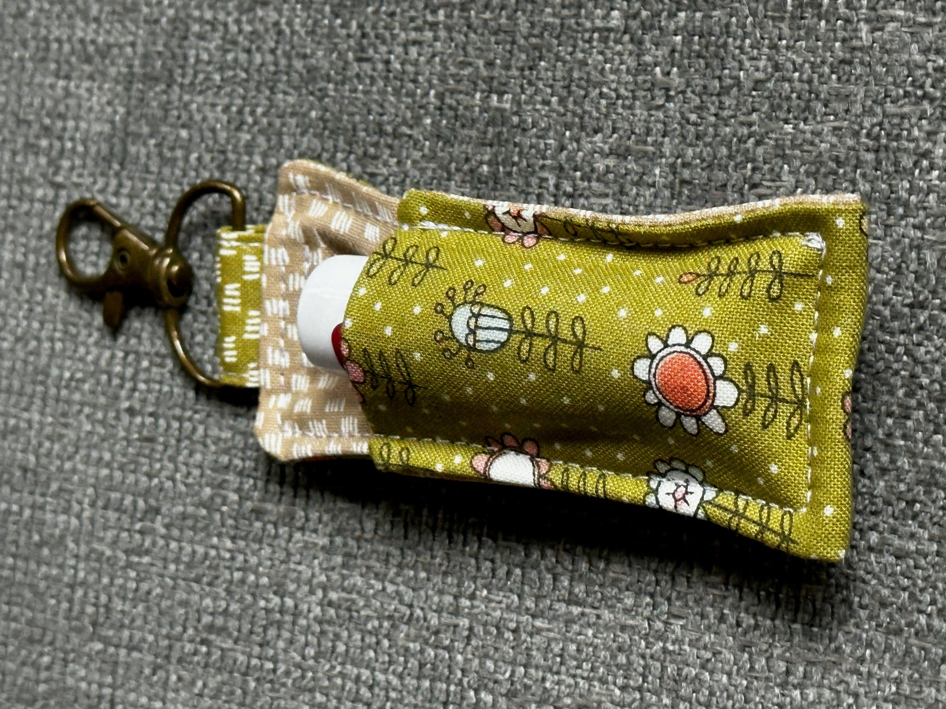 Fabric lip balm holder with floral design on a gray background