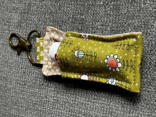 Fabric lip balm holder with floral design on a gray background