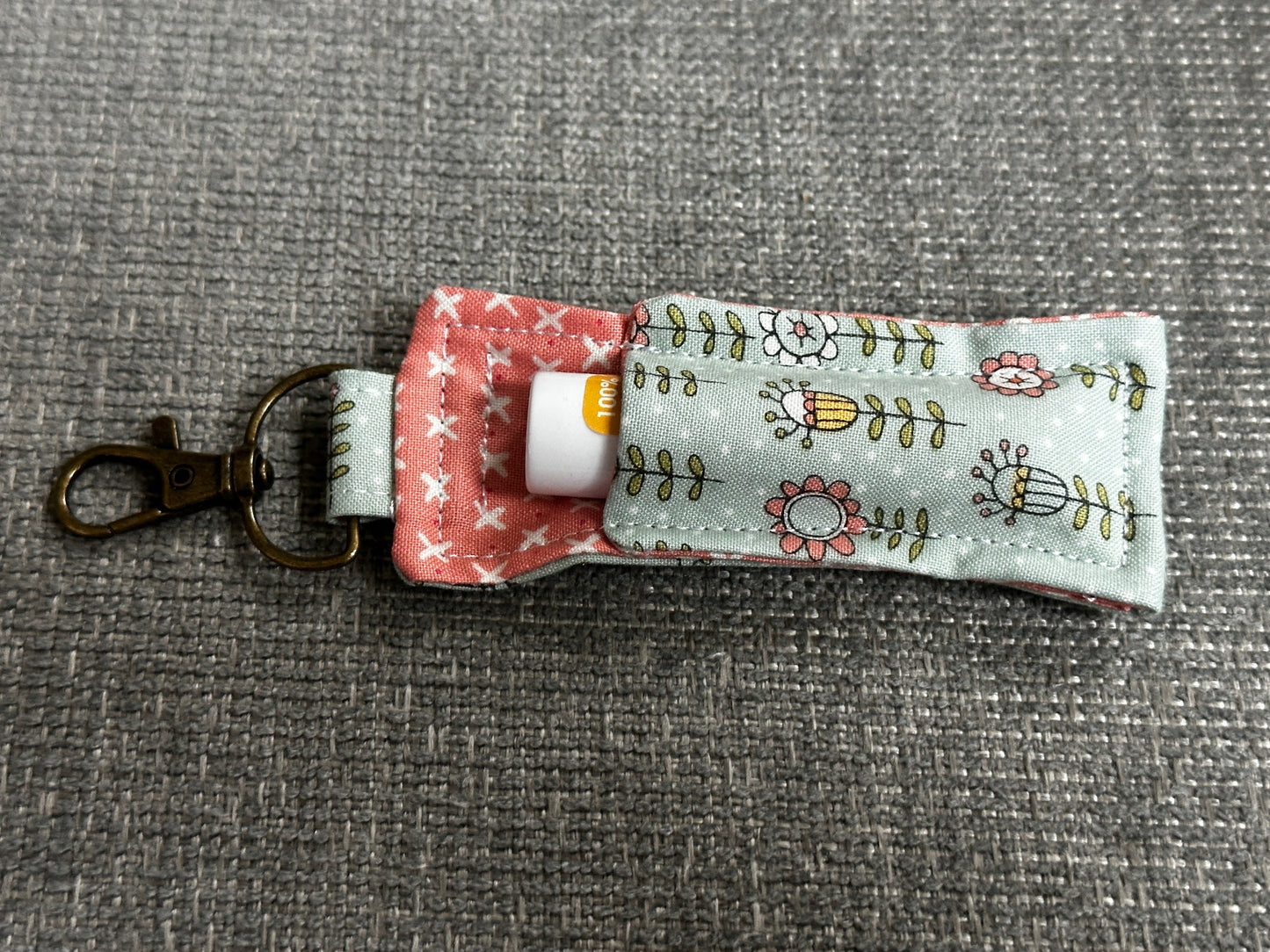 Keychain holder with floral design on a gray background