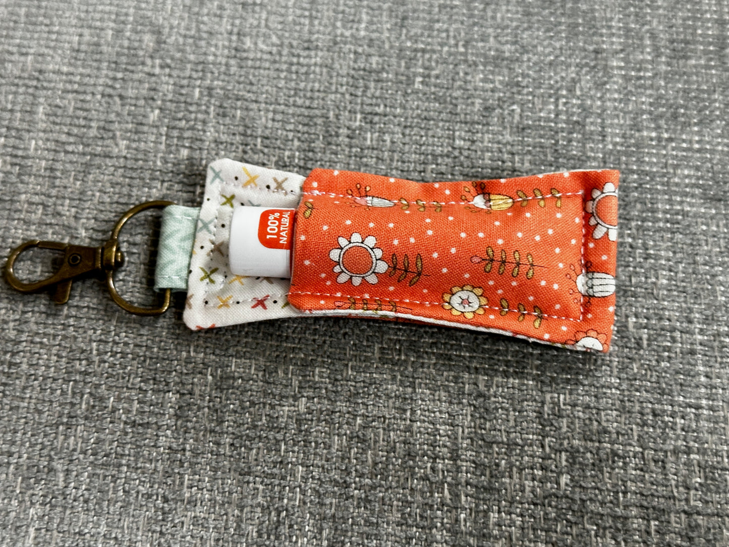 Fabric pouch with keychain attachment on a gray textured background