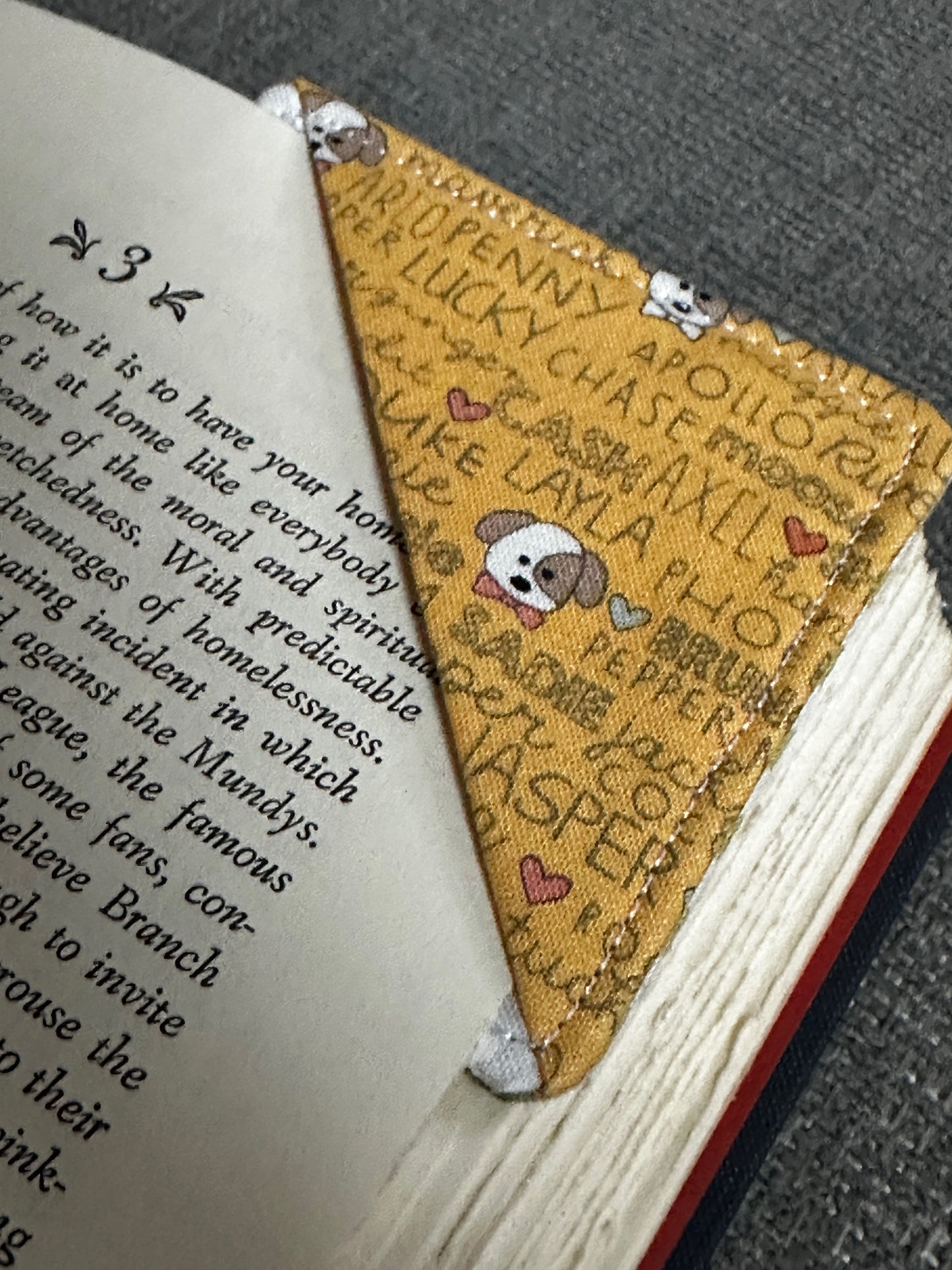 Handmade bookmark with embroidered text and designs on an open book