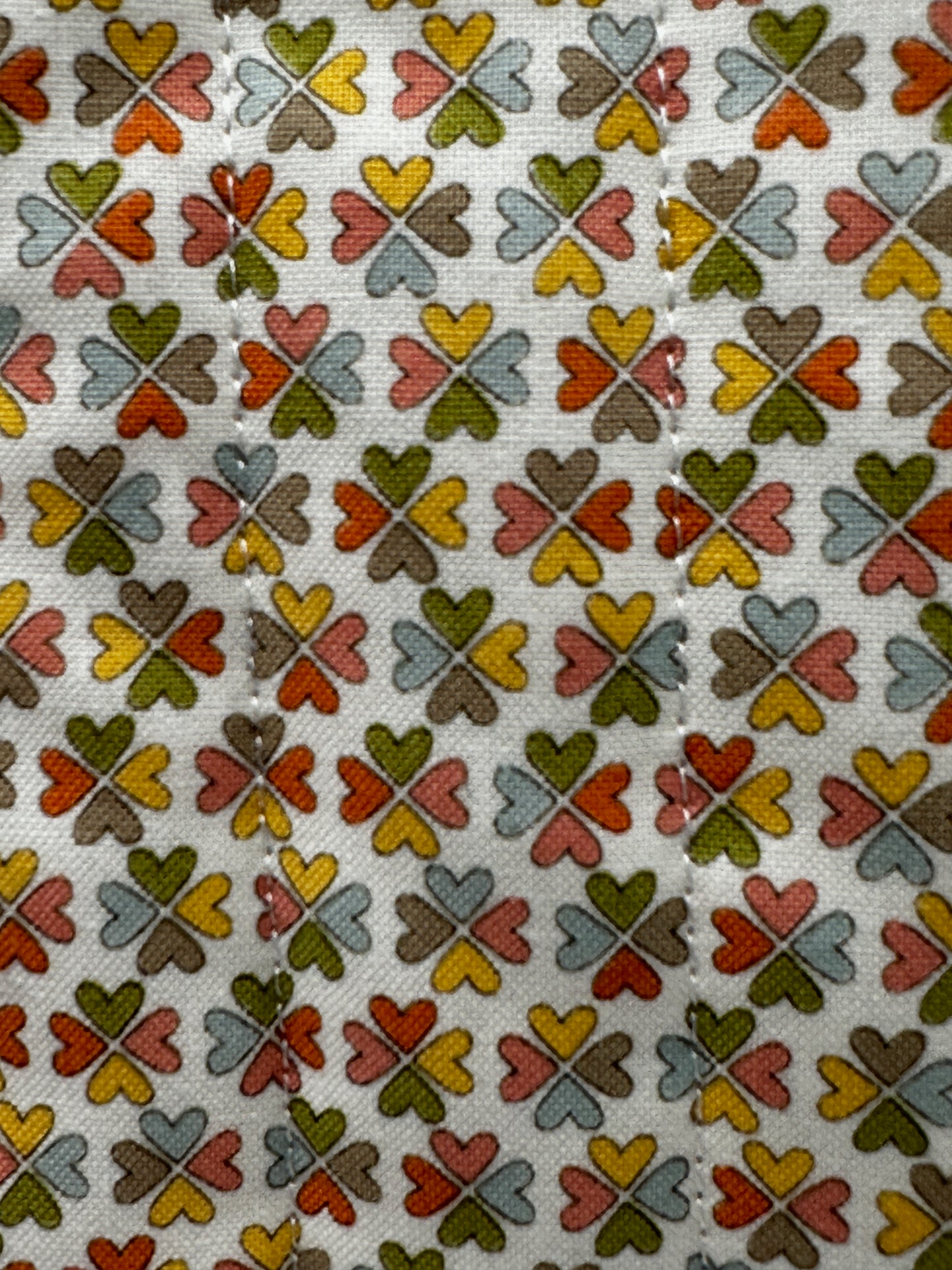 Patterned fabric with interlocking clover shapes in various colors on a beige background