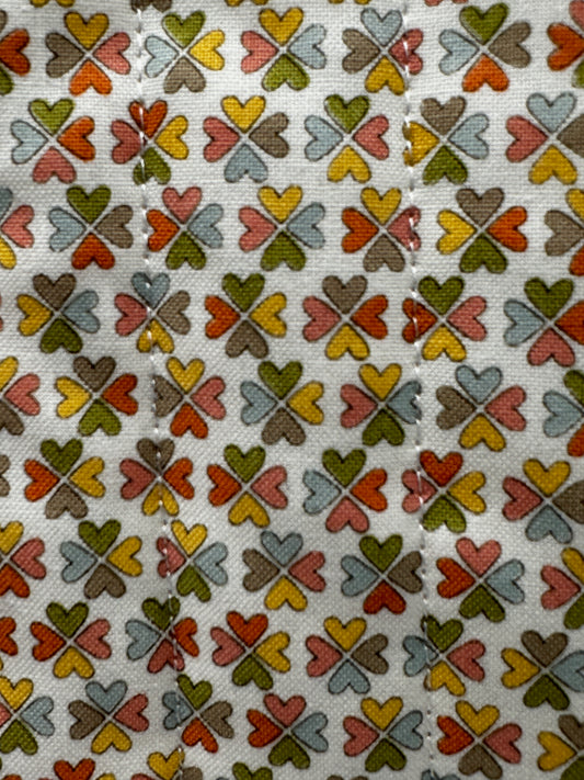 Patterned fabric with interlocking clover shapes in various colors on a beige background