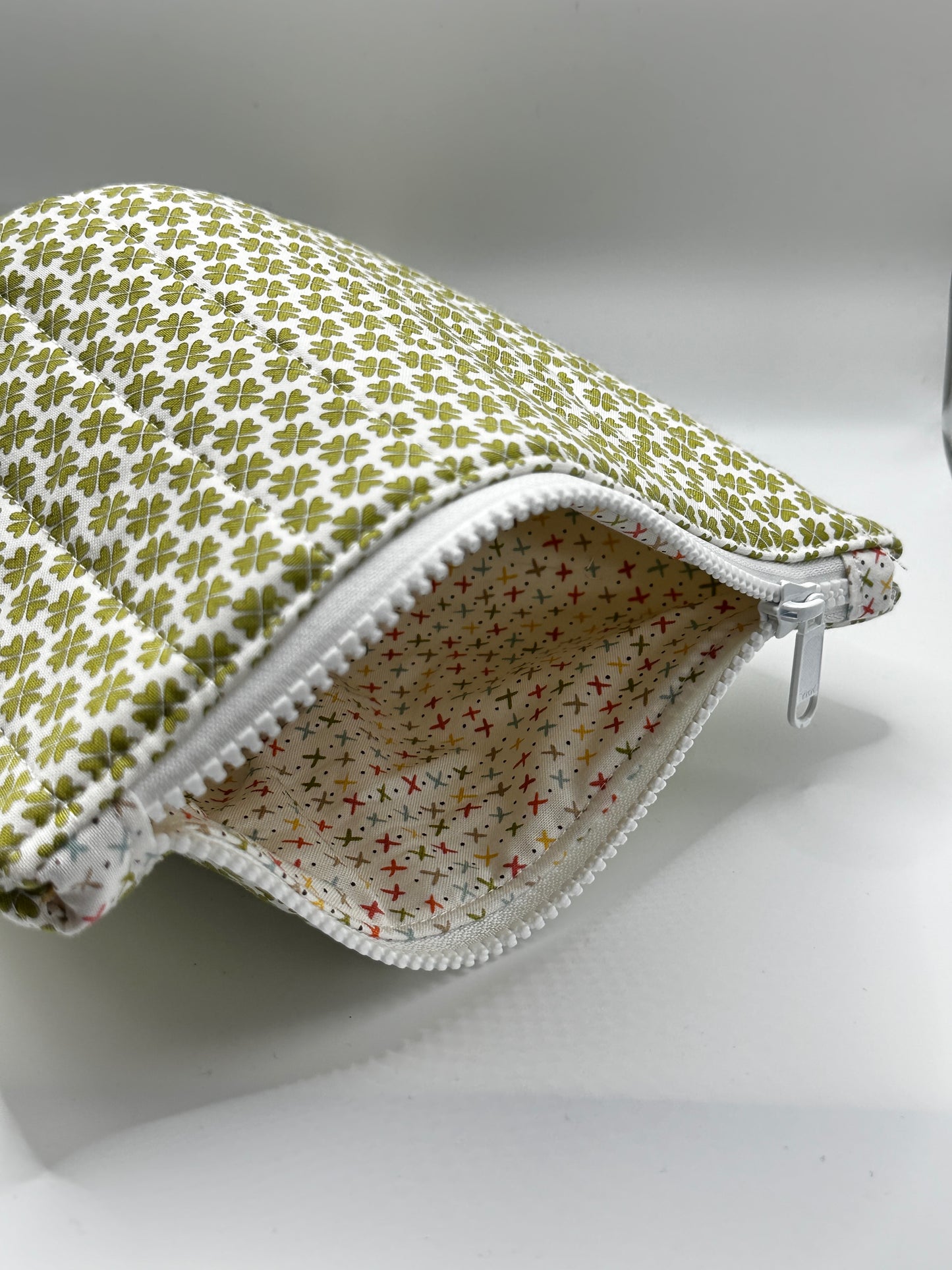 Fabric pouch with green clover pattern on a white background