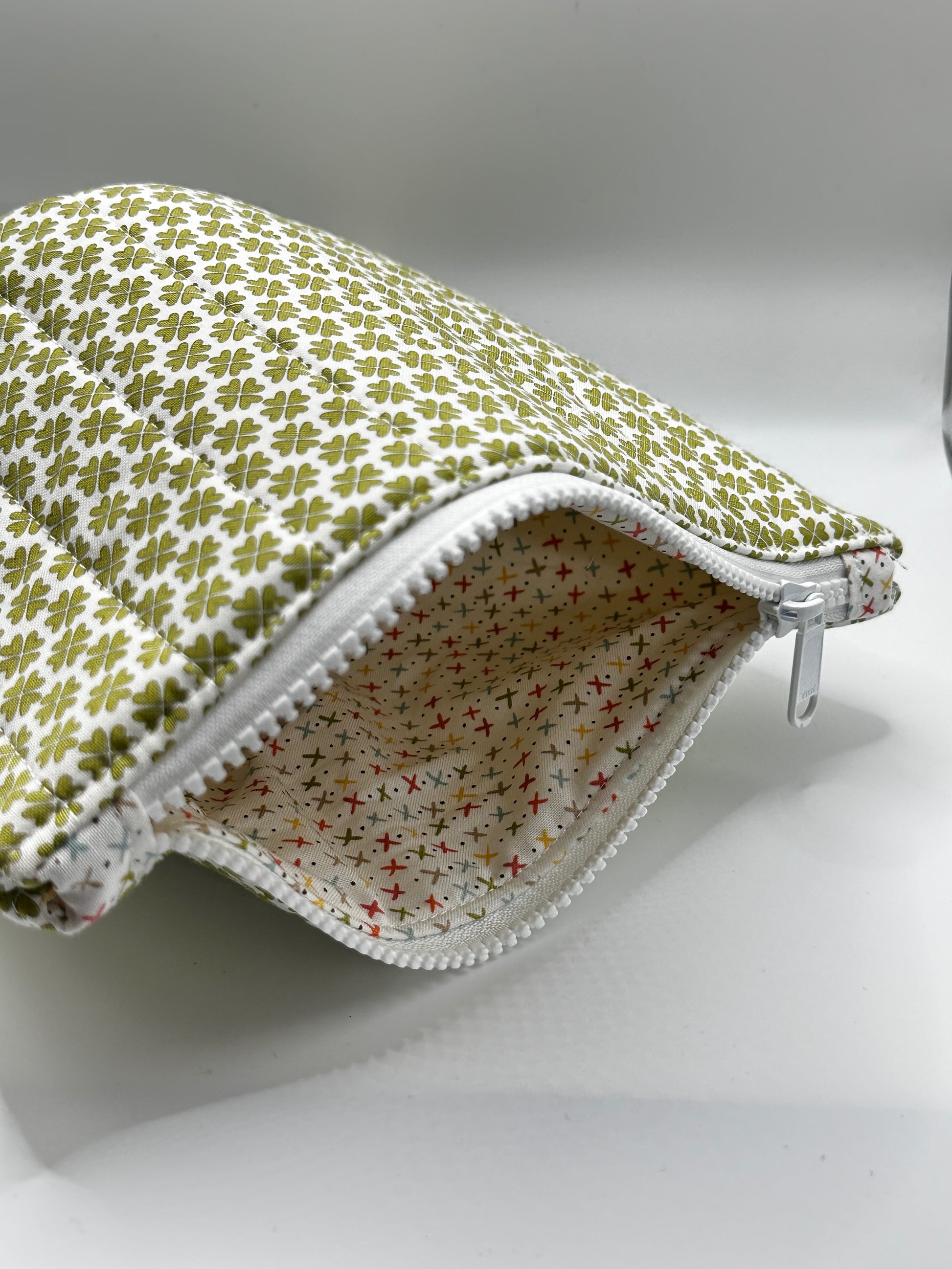 Fabric pouch with green clover pattern on a white background